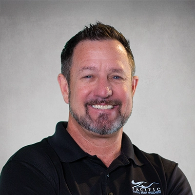 Paul Stately smiling in a black collared shirt.